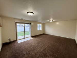 Carpeted spare room with a textured ceiling and baseboards
