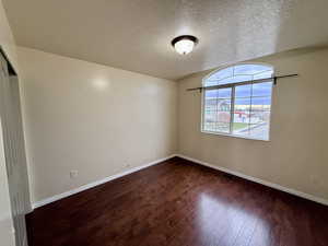 Spare room featuring a textured ceiling and dark wood-style floors