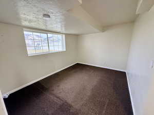 Spare room with a textured ceiling, carpet flooring, and a smoke detector