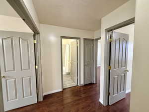 Hallway with dark wood-style flooring and a textured ceiling