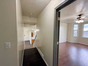 Hallway with a textured ceiling and dark wood finished floors