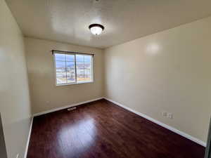 Empty room with dark wood-style floors and a textured ceiling