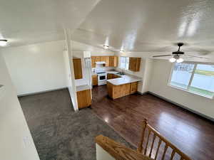 Kitchen with light countertops, open floor plan, electric range, a textured ceiling, and dark wood-type flooring