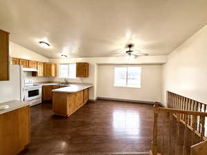 Kitchen featuring light countertops, white appliances, brown cabinets, healthy amount of natural light, and a textured ceiling