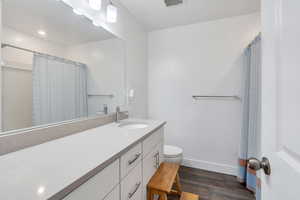 Featuring a large vanity and mirror, with large cabinet space and dark wood like flooring