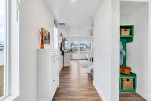Welcoming entry way with built in coat rack bench, living room and staircase to upper levels