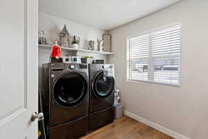 Laundry area featuring a textured ceiling, light wood-style flooring, and washing machine and clothes dryer