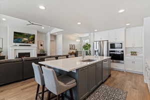 Kitchen featuring a kitchen bar, stainless steel appliances, open floor plan, white cabinetry, and recessed lighting