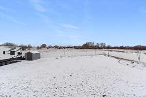 Snowy yard with a storage unit and a fenced backyard