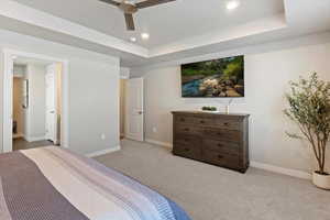 Bedroom featuring light carpet, ceiling fan, a tray ceiling, and recessed lighting