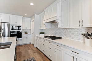 Kitchen featuring white cabinets, appliances with stainless steel finishes, light wood-style floors, light stone counters, and recessed lighting