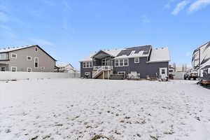Snow covered house featuring a fenced backyard, stairway, and a patio