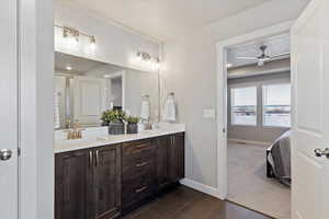 Ensuite bathroom with dark tile patterned floors, double vanity, a textured ceiling, a ceiling fan, and dark colored carpet