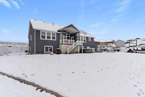 Snow covered back of property with stairway, a patio area, a balcony, and stucco siding