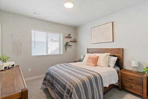 Bedroom featuring light carpet and a textured ceiling