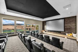 Carpeted cinema room with an accent wall, a raised ceiling, a glass covered fireplace, and recessed lighting