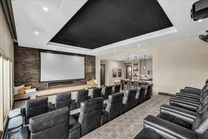 Cinema room featuring an accent wall, a tray ceiling, a fireplace, recessed lighting, and light colored carpet
