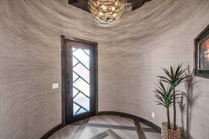 Entryway with a chandelier and wallpapered walls