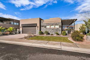 View of front of property with a pergola, stone siding, driveway, and stucco siding