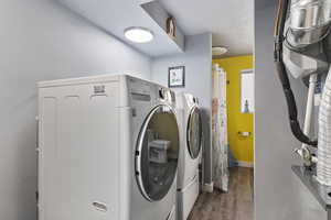 Laundry room featuring dark wood-style floors, washing machine and clothes dryer, and a textured ceiling