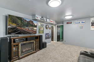 Carpeted cinema room with a lit fireplace