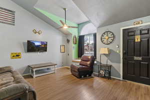 Living area with wood finished floors, ceiling fan, and lofted ceiling