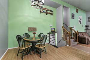 Dining room featuring wood finished floors, stairs, and a chandelier