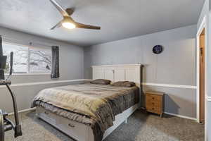 Carpeted bedroom with a textured ceiling and a ceiling fan