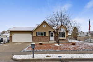 View of front of home featuring brick siding, driveway, and a garage