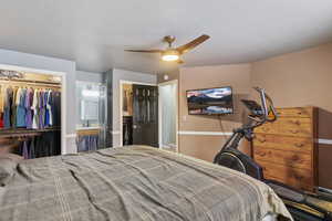Bedroom with ceiling fan, connected bathroom, a closet, and a textured ceiling