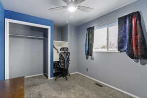 Carpeted office space featuring ceiling fan and a textured ceiling