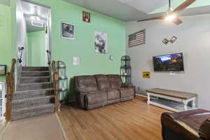 Living area with stairs, wood finished floors, and lofted ceiling