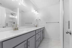 Full bathroom with a stall shower, double vanity, and light marble finish flooring
