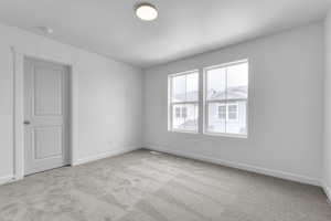 Empty room featuring light colored carpet and baseboards