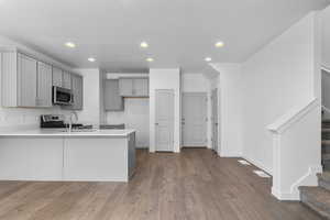 Kitchen featuring gray cabinetry, recessed lighting, stainless steel appliances, a peninsula, and dark wood finished floors