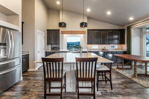 Kitchen with appliances with stainless steel finishes, a kitchen breakfast bar, recessed lighting, light stone counters, and pendant lighting