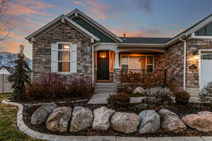 Craftsman-style house featuring stone siding, board and batten siding, an attached garage, and covered porch