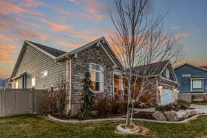 Property exterior at dusk with stone siding and a garage