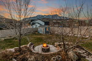 Fenced backyard featuring a mountain view, a shed, and a fire pit