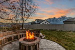Patio terrace at dusk featuring a fenced backyard, a patio area, and a mountain view
