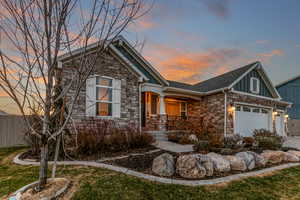 Craftsman-style house with stone siding, board and batten siding, a porch, a garage, and driveway