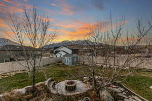 Back of house with a fenced backyard, a storage unit, an outdoor fire pit, and a mountain view