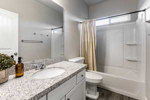 Bathroom with shower / bath combo with shower curtain, vanity, and dark wood-type flooring