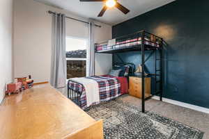 Carpeted bedroom with a ceiling fan and baseboards