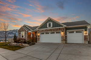 Craftsman house featuring board and batten siding, concrete driveway, stone siding, an attached garage, and roof with shingles