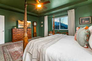 Bedroom featuring a textured ceiling, ceiling fan, and a raised ceiling