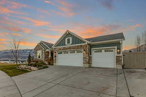 Craftsman-style house featuring board and batten siding, stone siding, an attached garage, and concrete driveway