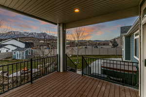 Wooden terrace with a mountain view, a storage unit, and a fenced backyard
