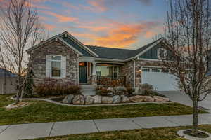 Craftsman-style house featuring board and batten siding, stone siding, covered porch, and driveway