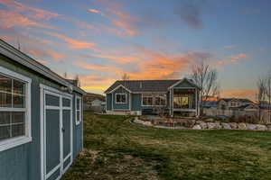 Back of property featuring a fire pit, an outbuilding, and a patio
